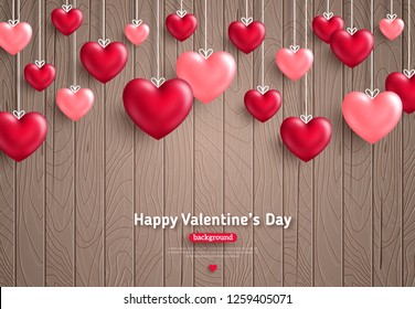 Happy Saint Valentine's day card, hanging hearts on brown wooden background with place for text.