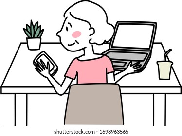 Happy senior woman sitting at desk, staring at mobile phone screen while using computer doing work. Cute mature woman sitting at desk with laptop and reading message or video call on smartphone.