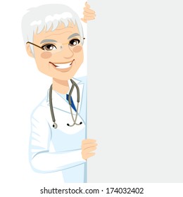 Happy smiling professional senior male doctor peeking out of a blank billboard sign