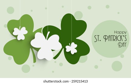 Happy St. Patrick's Day celebration with hanging shamrock leaves on green background.