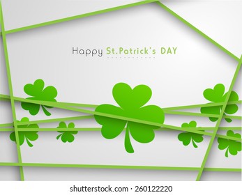 Happy St. Patrick's Day celebration with shiny shamrock leaves on grey background.