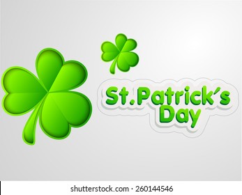 Happy St. Patrick's Day celebration with glossy Irish lucky shamrock leaves on grey background.