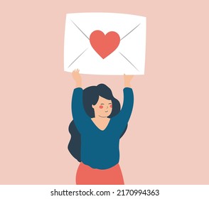 Happy teenage girl lifts up a large envelope with a red heart. Woman holding a big white envelope with a red heart. Girl transmet a message above her head. Concept of valentines day, love and romance.