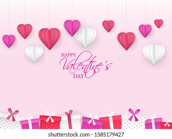 Happy Valentine's Day Celebration Concept with Hanging Paper Cut Hearts and Gift Boxes Decorated on Pink Background.