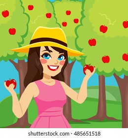 Happy woman harvesting apples from orchard tree on autumn