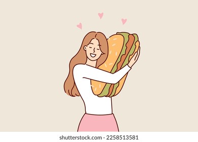 Happy woman hugging giant hamburger missing fast food after long diet to maintain slim figure. Girl smiling broadly holding big hamburger in hands enjoying lunch break during exhausting work