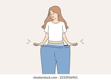 Happy woman lost weight smiles while trying on large size pants and rejoices at progress. Thin lady got rid of waist fat and cellulite thanks to successful diet or fitness training