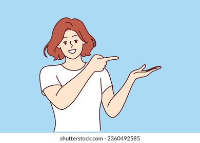 Happy woman pointing at copy space and raising palm up to demonstrate advertised product. Girl promoter in casual t-shirt with smile recommends placing your marketing offer on copy space