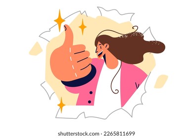 Happy woman showing thumbs up in agreement peeking out of hole in torn advertising banner. Girl makes thumbs up gesture to invite you to shopping in mall during sale period with big discounts 