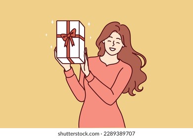 Happy woman shows gift box with red ribbon given by boyfriend in honor of birthday or christmas eve. Positive girl shows off gift she received after participating in promotion from clothing store 