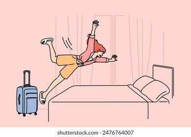 Happy woman tourist jumps on hotel bed, rejoicing at onset of vacation and opportunity to visit sunny resort. Girl with travel suitcase is in hotel and happily plops down on bunk to relax