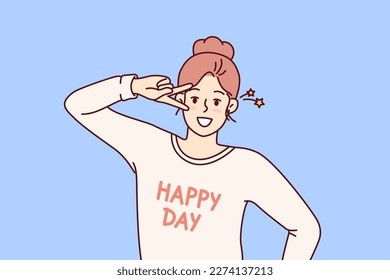 Happy woman waving hand demonstrating letter V with fingers and looking at camera wishing you happy day. Woman with happy day lettering on t-shirt as sign of greeting makes victory gesture