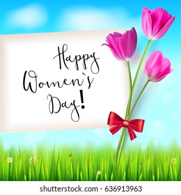 Happy women day, greetings card. Pink tulips on the blue summer sky backdrop. Green grass and white clouds. Hand-drawn inscription. Template for your invitation, cover or greetings.