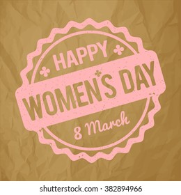 Happy Women's Day rubber stamp baby pink on a crumpled paper brown background.