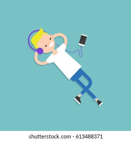 Happy young blond boy with headphones listening to music on a floor. Top view / flat editable vector illustration