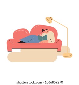 Happy young boy relaxing on sofa and reading book at home