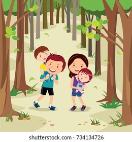 Happy young family walking in forest. Young parents enjoying with their two little kids while taking a walk in nature.