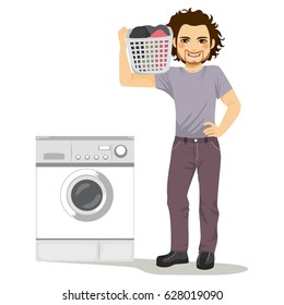Happy young man holding laundry basket doing chores with washing machine