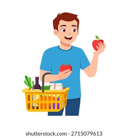 Hombre joven feliz que sostiene dos manzanas rojas y una cesta de la compra llena de comestibles sonriendo y mirando complacido