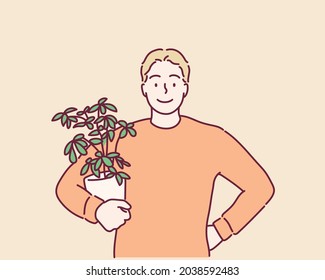 Happy young man holds a pot with decoration plant. Hand drawn style vector design illustrations.