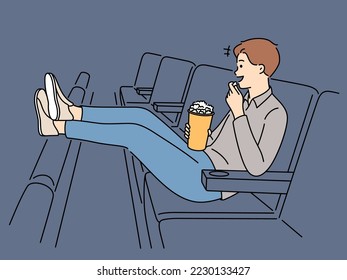 Happy young man with popcorn sit in chair enjoy movie in cinema. Smiling guy watch film in theater on weekend. Hobby and entertainment. Vector illustration. 