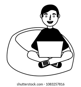 happy young man sitting bean bag in chair with laptop