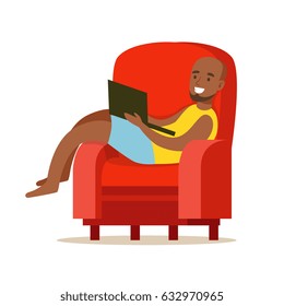 Happy young man sitting in a red armchair and using laptop, colorful character vector Illustration