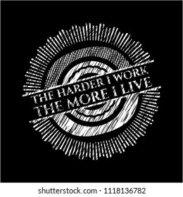The Hardest I work the More I Live chalk emblem written on a blackboard
