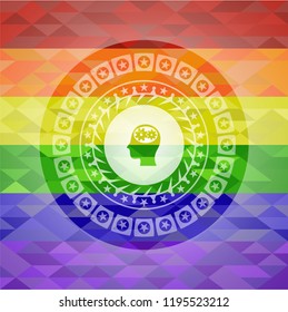 head with gears inside icon inside emblem on mosaic background with the colors of the LGBT flag