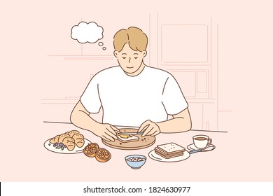 Health, care, food, thinking concept. Young thoughtful smiling pensive man boy character making toast spreading butter on bread at breakfast lunch dinner at home kitchen. Healthy eating lifestyle