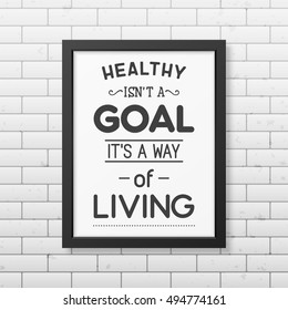 Healthy is not a goal it is a way of living- Typographical Poster in the realistic square black frame on the brick wall background. Vector EPS10 illustration.