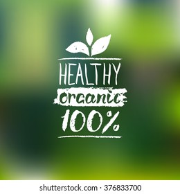 Healthy Organic 100% vector logo with handwritten lettering. Eco food label on blur background. Bio sign, badge for vegetarian restaurant, vegan cafe, product packaging. 