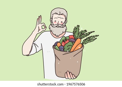 Healthy vegan food and lifestyle concept. Young happy positive elderly man cartoon character standing and holding basket with fresh raw organic vegetables and fruits in hands vector illustration 