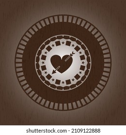 heart with arrow icon inside badge with wooden background. 