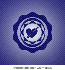 heart with arrow icon inside emblem with denim texture. 