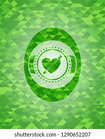 heart with arrow icon inside green emblem. Mosaic background