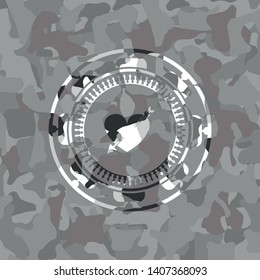 heart with arrow icon inside grey camouflage emblem