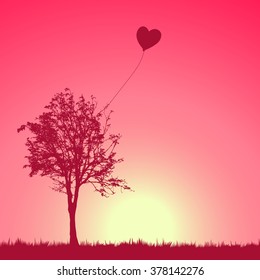 A heart balloon stuck in a tree.