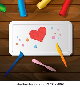 The heart of plasticine on the board for crafts on a wooden table and stacks. clay effect