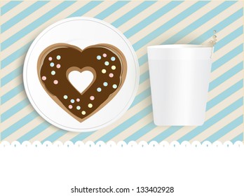 Heart shaped chocolate doughnut decorated with sprinkles on a plate alongside a white cup with blank white copyspace below