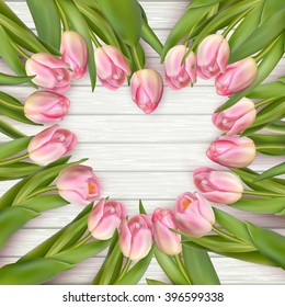 Heart shaped romantic frame of fresh spring tulips arranged with radiating stems and the flowers forming the heart over wooden background with copy space. EPS 10 vector file included