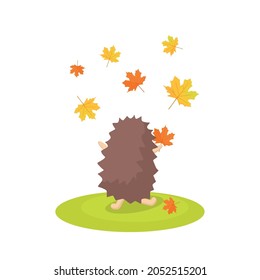 The hedgehog stands with his back and throws autumn leaves in the air. Vector cartoon illustration.