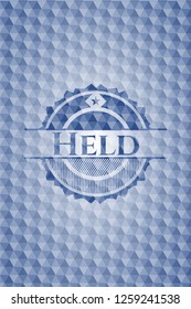 Held blue emblem with geometric pattern background.