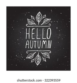 Hello Autumn. Hand-sketched typographic element with autumn leaves on chalkboard background. 