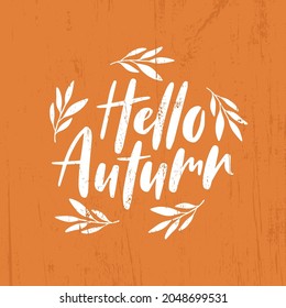 Hello autumn lettering quote with September leaves. Fall season decoration. Autumn greeting card. Typography template for poster, flyer, web banner. Vector illustration isolated on orange background.