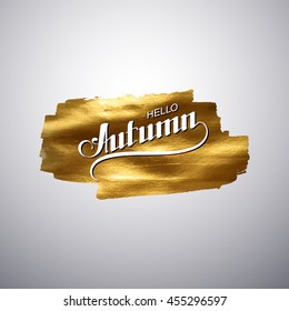 Hello Autumn. Seasonal vector illustration of handwritten label on golden paint stain banner. Vector gold paint. Autumn lettering composition with gold glittering textured stain.