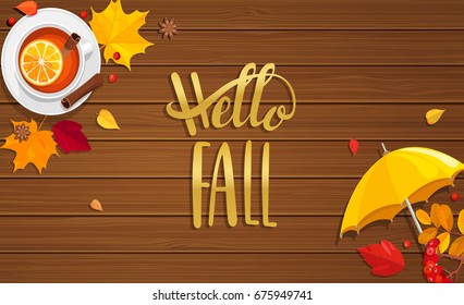 Hello Fall lettering on wooden background with hot spiced tea, umbrella and autumn leaves. Vector illustration.