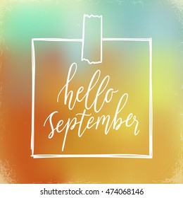 Hello September, hand lettering calligraphic word. greeting card template, vector typographic illustration with handwritten words about autumn on a blurred background