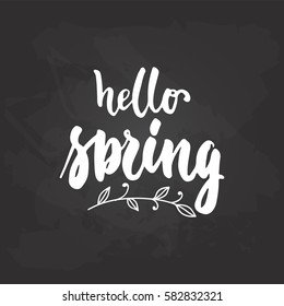 Hello, spring - hand drawn lettering phrase isolated on the black chalkboard background. Fun brush ink inscription for photo overlays, greeting card or t-shirt print, poster design