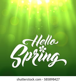 HELLO SPRING Hand lettered style spring background. Handmade vector calligraphy on abstract glowing green background with  bokeh light and sun beams
